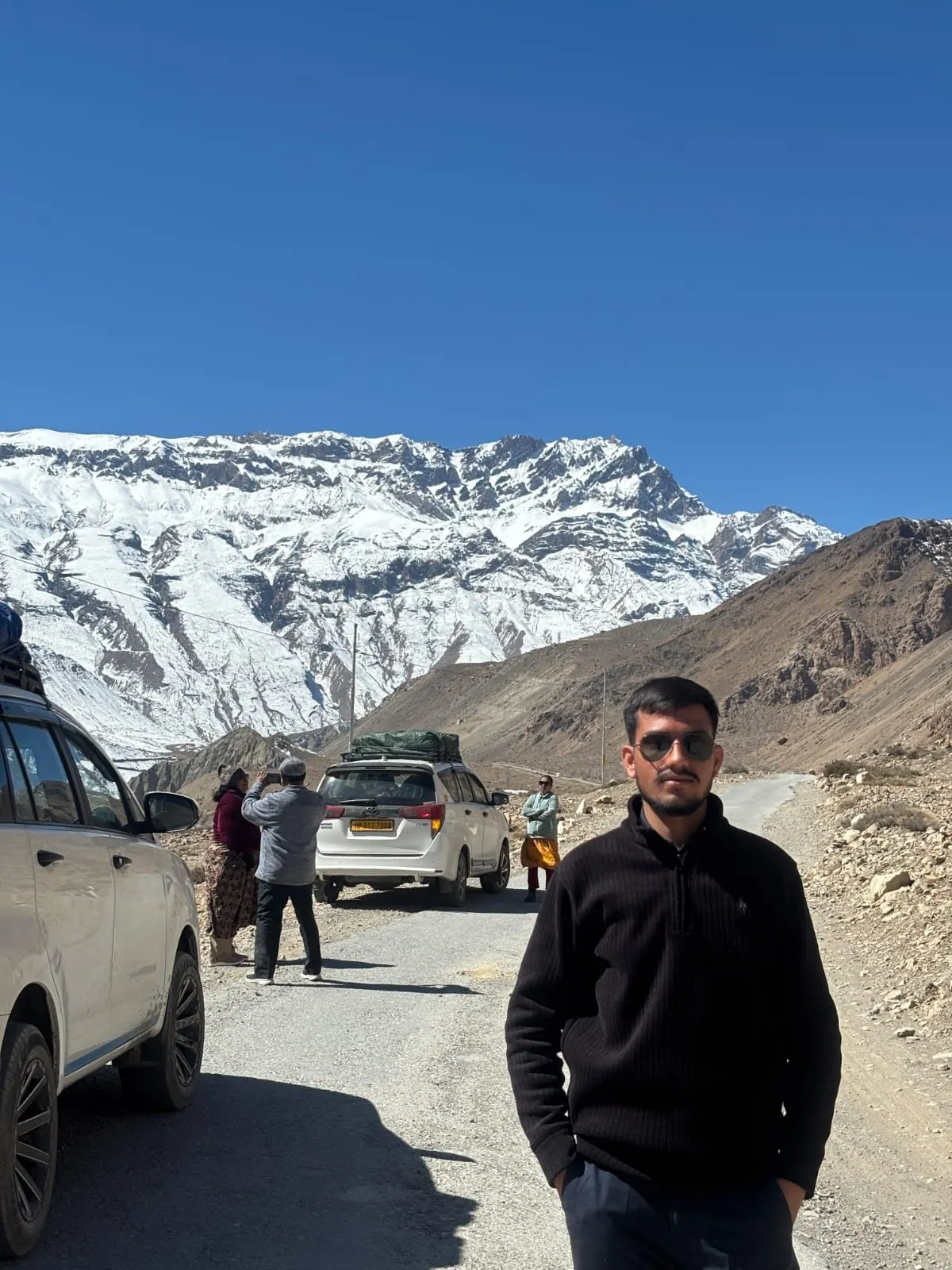 Kulwant standing roadside at Tabo, snow-capped peaks behind him